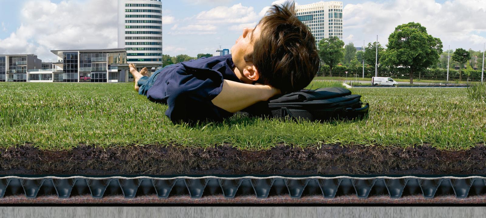 Mann liegt auf einem Rasen über einem Gründach-Systemaufbau