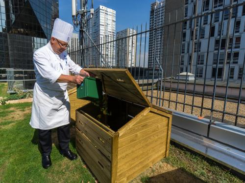 Koch wirft Abfälle in einen Kompostbehälter auf dem Dach